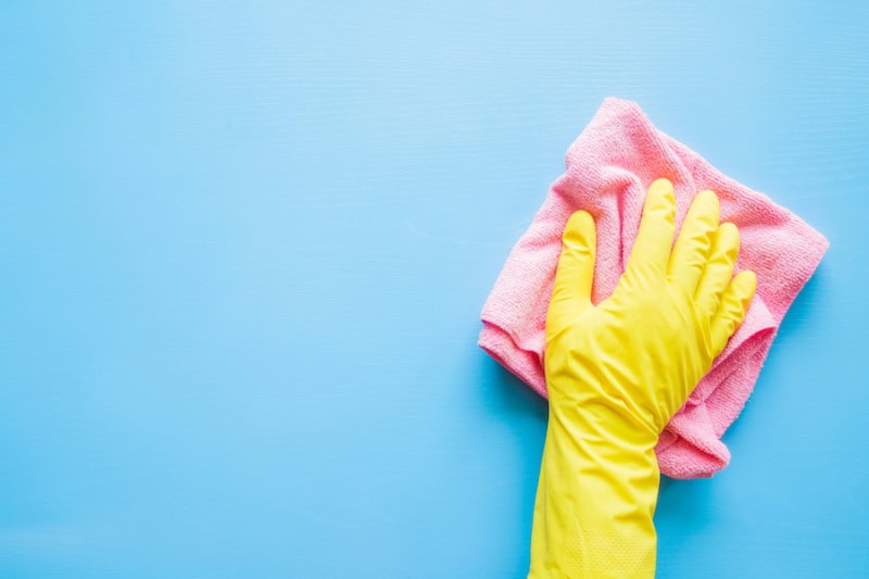 Does an AC Kill Mold? Employee hand in rubber protective glove with microfiber rag wiping blue table, wall or floor surface in room, bathroom, kitchen.