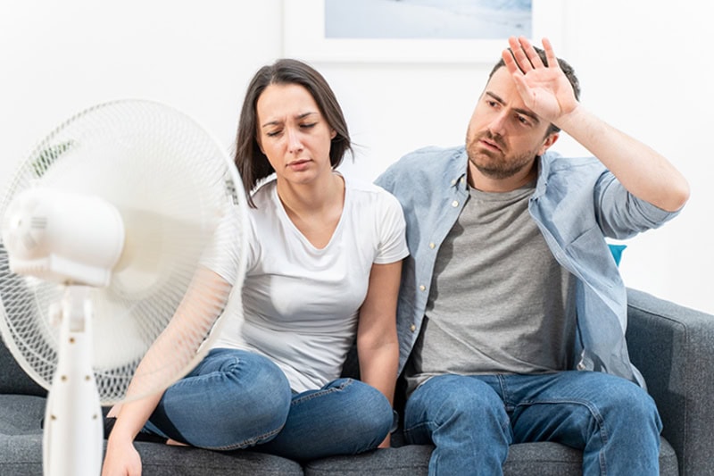 5 Reasons Why Regular HVAC Maintenance is Essential for Homeowners. Couple trying to refresh during summer heat wave.