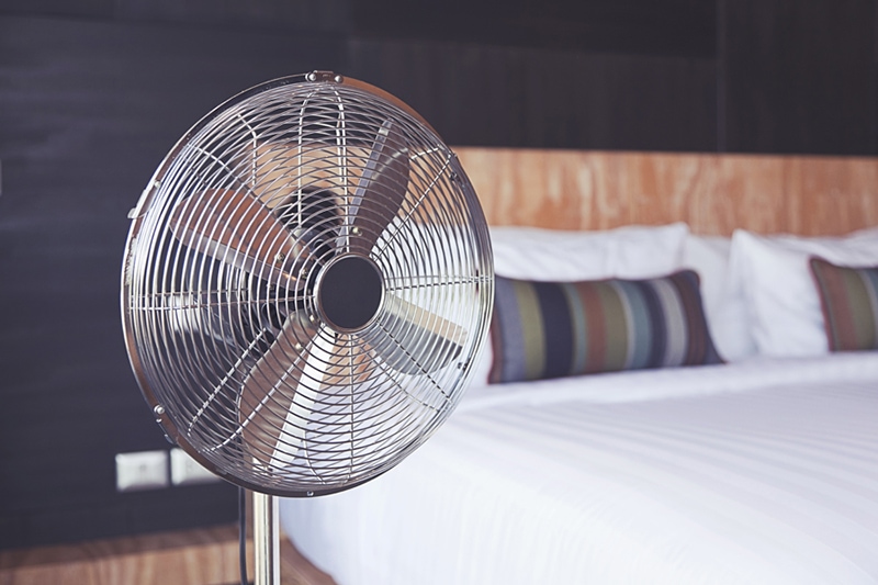 Improve your home's indoor air quality. Old electric fan near the bed in the room.